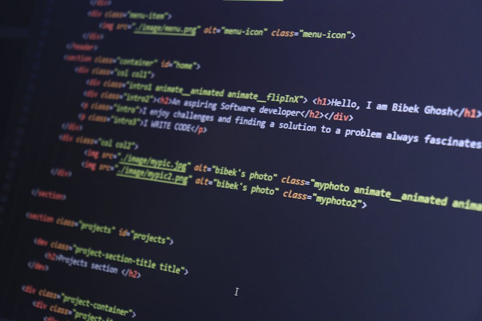 A person working on a laptop computer displaying lines of code in a dark-themed programming environment. The laptop is placed on a smooth, dark surface and the user's hands are actively typing on the 